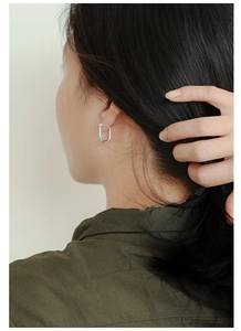 Silver U-shaped oval earrings on a female model shown from a side profile view