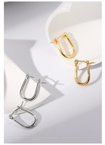 Detail view of U-shaped gold and silver horseshoe earrings with polished metal finish