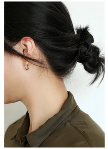 Detail view of gold-plated brass U-shaped horseshoe earring on a female model's ear