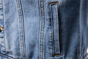 Detailed close-up of double-stitched pocket seams on classic blue denim jacket for men