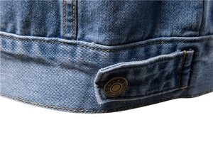 Detail of denim jacket hem with metal buttons and classic contrast stitching on blue fabric