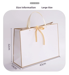 Detailed view of a large white gift bag with gold bow showing dimensions 43x14x32cm