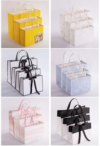 Multiple sizes and designs of glossy white cardboard gift bags with bow handles