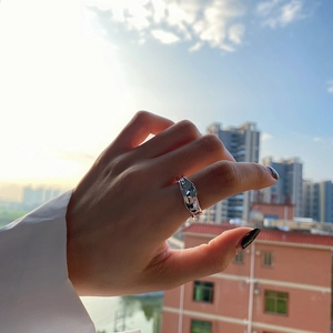 Irregular liquid lava texture silver ring worn on index finger with backlit urban background