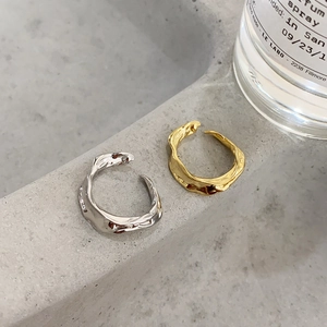 Detailed shot of irregular lava-style open rings in gold and silver on grey stone