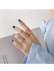 Close-up of irregular wave rings in gold and silver finish on hand with black french nails