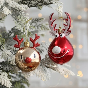 Red and gold reindeer Christmas tree ornaments with glitter on snowy pine branches