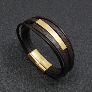 Detail view of multi-layer brown leather bracelet with gold metal bars and magnetic clasp