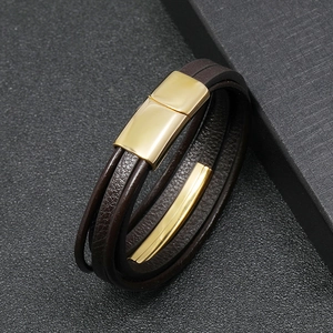 Macro shot of men's brown braided leather bracelet with a polished gold magnetic clasp
