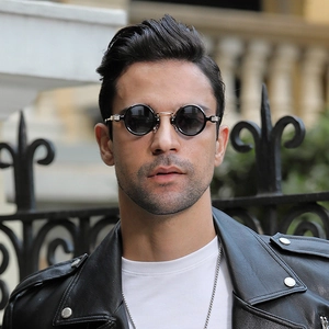 Close-up of steampunk round sunglasses with black lenses and gold bridge on a model
