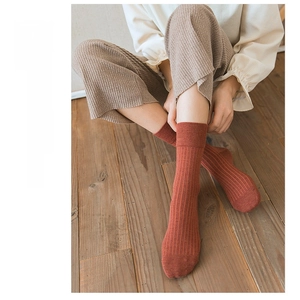 Close-up of brick red ribbed cotton crew socks on wooden floor background