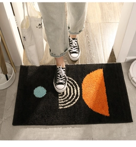 Modern absorbent doormat with geometric patterns shown in use on wooden floor
