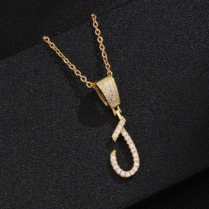 Macro shot of gold letter J pendant necklace with micro-pave white zircon settings