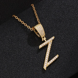 Macro shot of gold-plated Z-letter pendant with pavé zircon stones on black leather