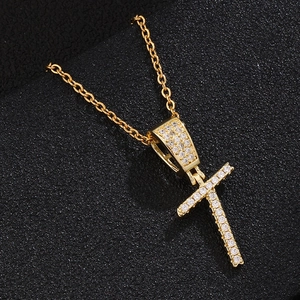 Detail view of a gold-plated cross pendant with micro-pave zircons on a black background