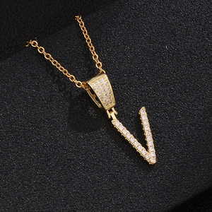 Macro shot of gold V letter pendant with micro-paved zircons on a fine chain