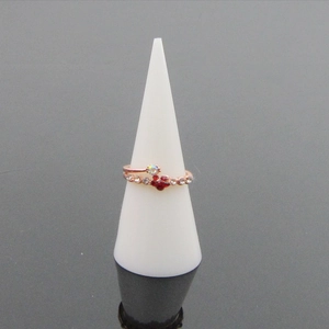Anello in oro rosa con fiore di cristallo rosso e bianco su supporto conico bianco