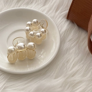 Detailed close-up of elegant pearl hair claws displayed on a decorative ceramic plate