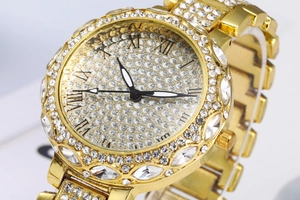 Gros plan d'une montre dorée pour femme avec lunette en cristal et cadran romain