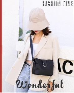Chic black nylon crossbody bag with wide strap styled on a model in a beige suit