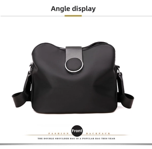 Front view of a minimalist black nylon crossbody bag with round metal ring buckle and strap