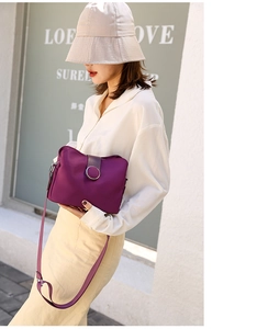 Detail of purple nylon bucket bag with round metal buckle shown on a model street style