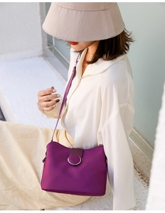 Detail of purple crossbody mini bag featuring a stylish round metal buckle and smooth finish