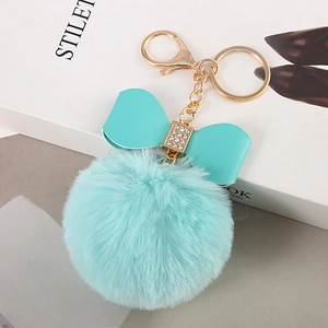 Detail of light blue fluffy pompom keychain with faux rabbit fur and rhinestone bow charm