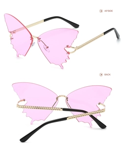 Detail view of pink butterfly-shaped rimless sunglasses with gold chain-textured temples