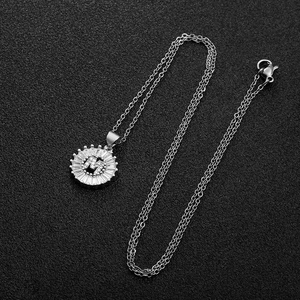 Vue macro du pendentif lettre M argenté avec zircons sur un fond noir texturé
