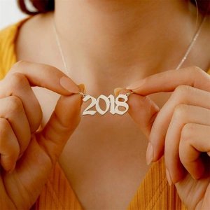 Close-up of a custom silver 2018 year number necklace worn by a model as a gift