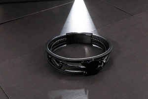 Detail of multi-layer black leather bracelet with mini guitar pendant and magnetic clasp