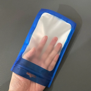 Close-up of a hand holding a blue matte and transparent resealable storage bag with hanging hole