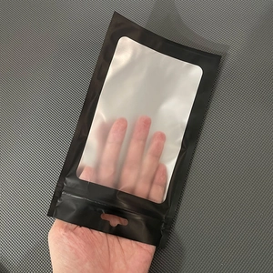 Matte black stand-up foil pouch with clear window and hang hole being held by hand