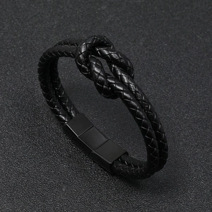 Detail of black braided leather bracelet featuring a magnetic steel clasp and knot design