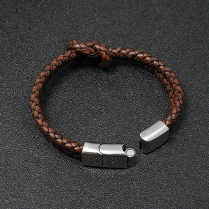 Brown braided leather bracelet with stainless steel magnetic clasp on black surface