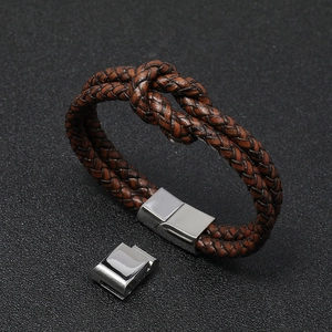 Braided brown leather bracelet with magnetic stainless steel clasp on a black surface