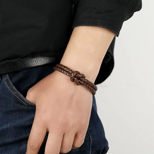 Brown braided leather bracelet with knotted design on a male wrist with denim jeans