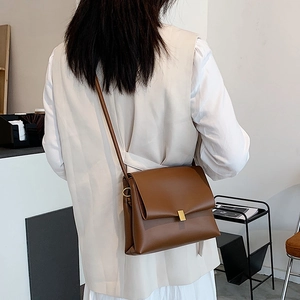 Borsa a tracolla vintage in pelle marrone con chiusura dorata indossata da una modella