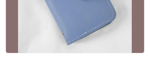 Macro detail of light blue lychee pattern leather card holder with white stitching and rivet