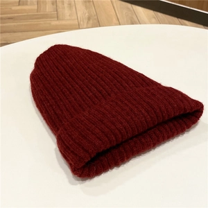 Dettaglio del berretto in maglia bordeaux con trama a costine su base bianca