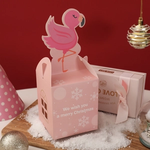 Pink flamingo Christmas gift box with Merry Christmas greeting on snowy wooden tray
