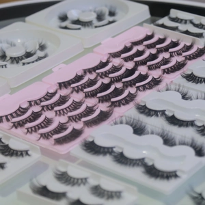 Detailed view of black faux mink eyelashes arranged in white and pink storage trays