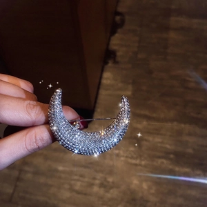 Sparkling silver crescent moon brooch with full crystal inlay held in hand