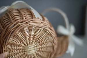 Close-up of hand-woven wicker basket base with white silk ribbon decoration