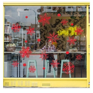 Red snowflake window stickers shown in a cozy cafe window setting for festive decoration
