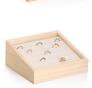 Close-up of solid wood ring display tray with cream velvet slots and sloped design