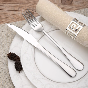Polished silver stainless steel cutlery set with serrated knife on a wooden table