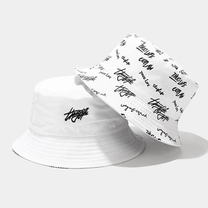 Dettaglio di cappelli a secchiello in cotone bianco con ricamo Thug Life e stile graffiti