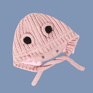 Detail of pink knitted baby hat featuring cartoon 3D eyes and warm earflaps with ties